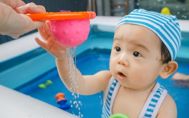 にぎにぎカップから水が流れるのを見る赤ちゃん,