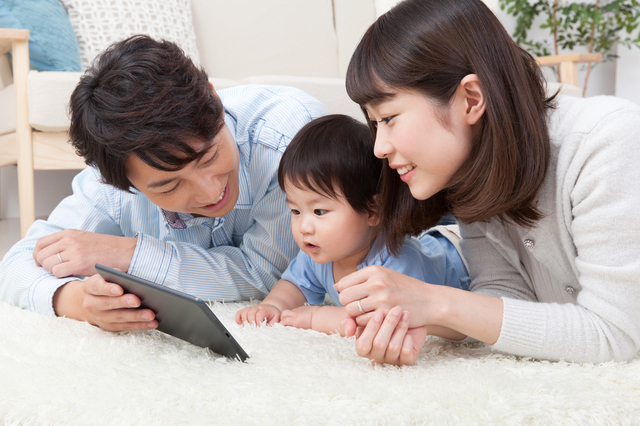 タブレットを見ている親子三人,絵本,読み聞かせ,アプリ